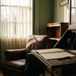 Worn leather armchair beside an antique mahogany writing desk with a blank document and fountain pen in soft afternoon window light.